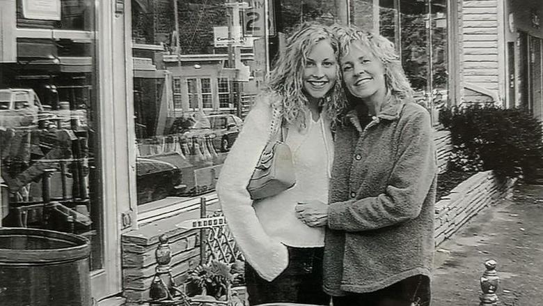 这是一张黑白照片，两名女子手挽着手站在一家企业外面.
